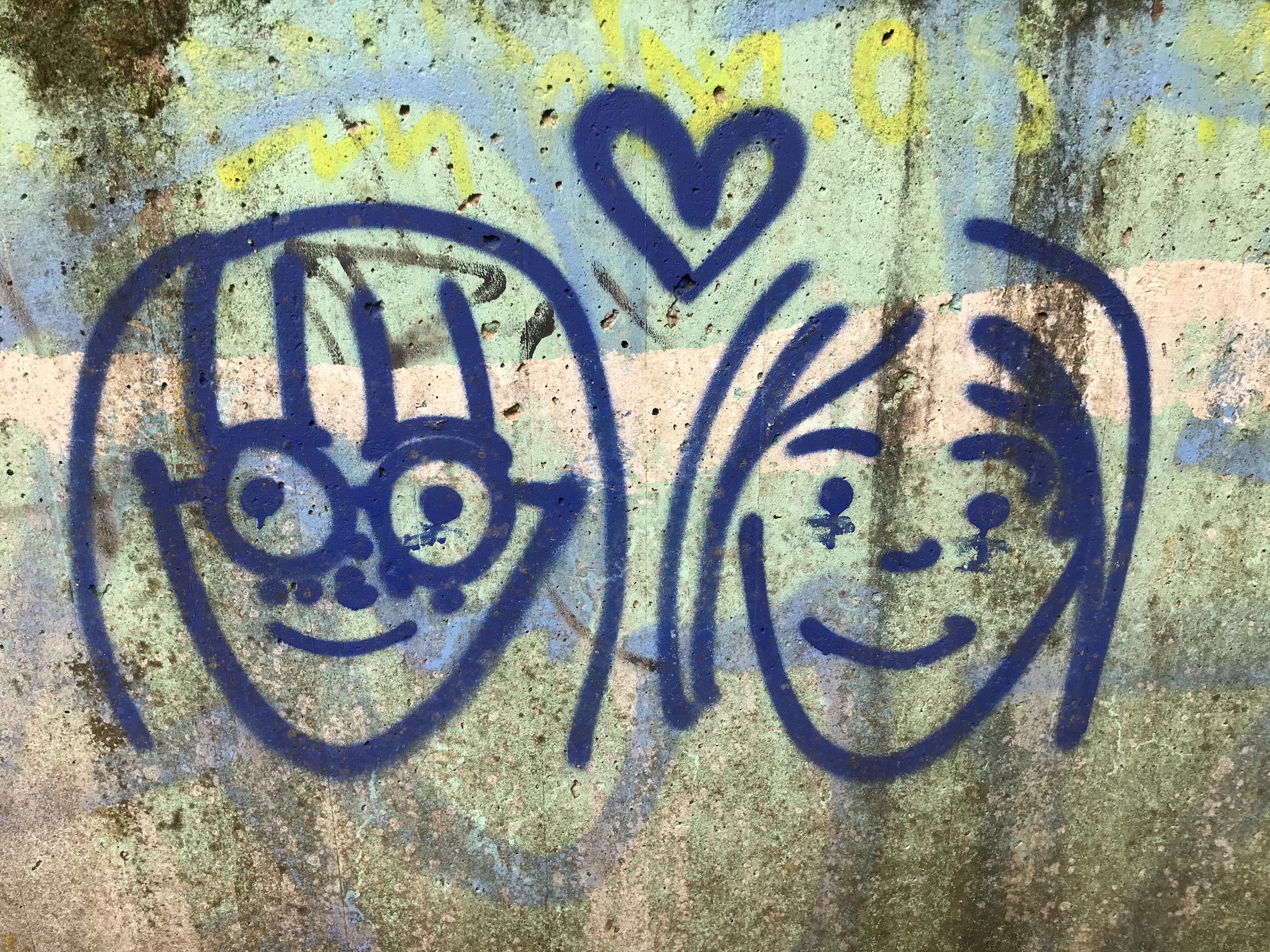Graffiti in einer Unterführung: zwei freundliche Frauengesichter, darüber ein Herz