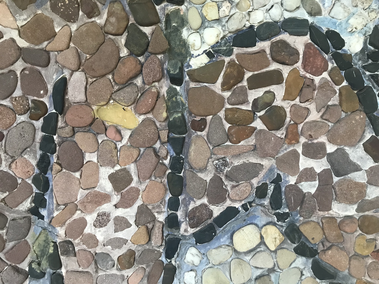 Aus dem Schlossgarten Oldenburg: Ausschnitt eines Wandmosaiks aus Kieselsteinen: angewinkelte Beine