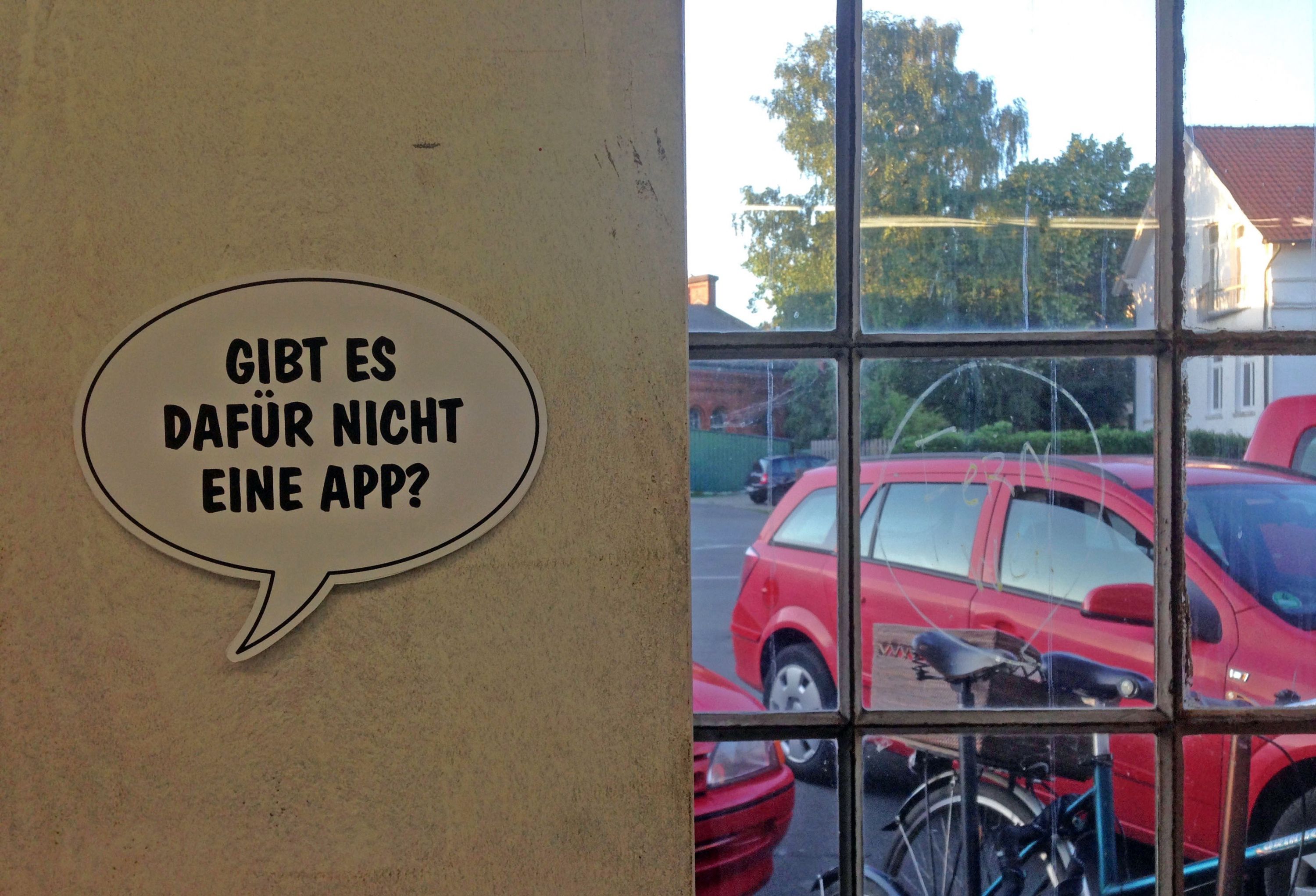 Sprechblase „Gibt's dafür nicht eine App?“ auf Innenwand mit Blick durch Fenster nach draußen