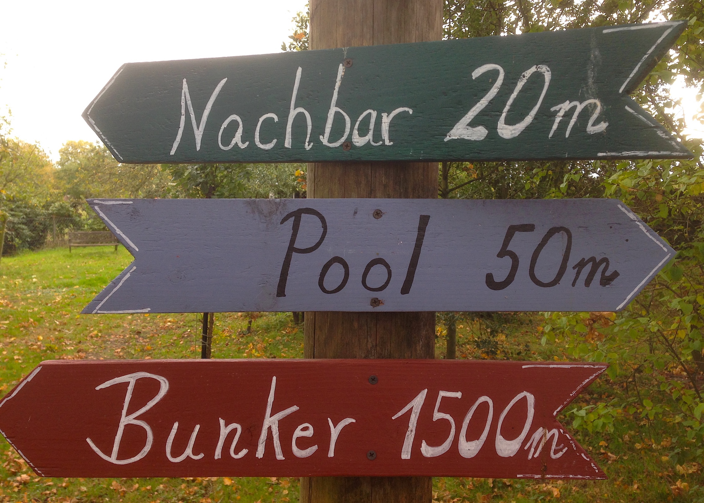 Handgeschriebene Wegweiser: Nachbar 20m, Pool 50m, Bunker 1500m
